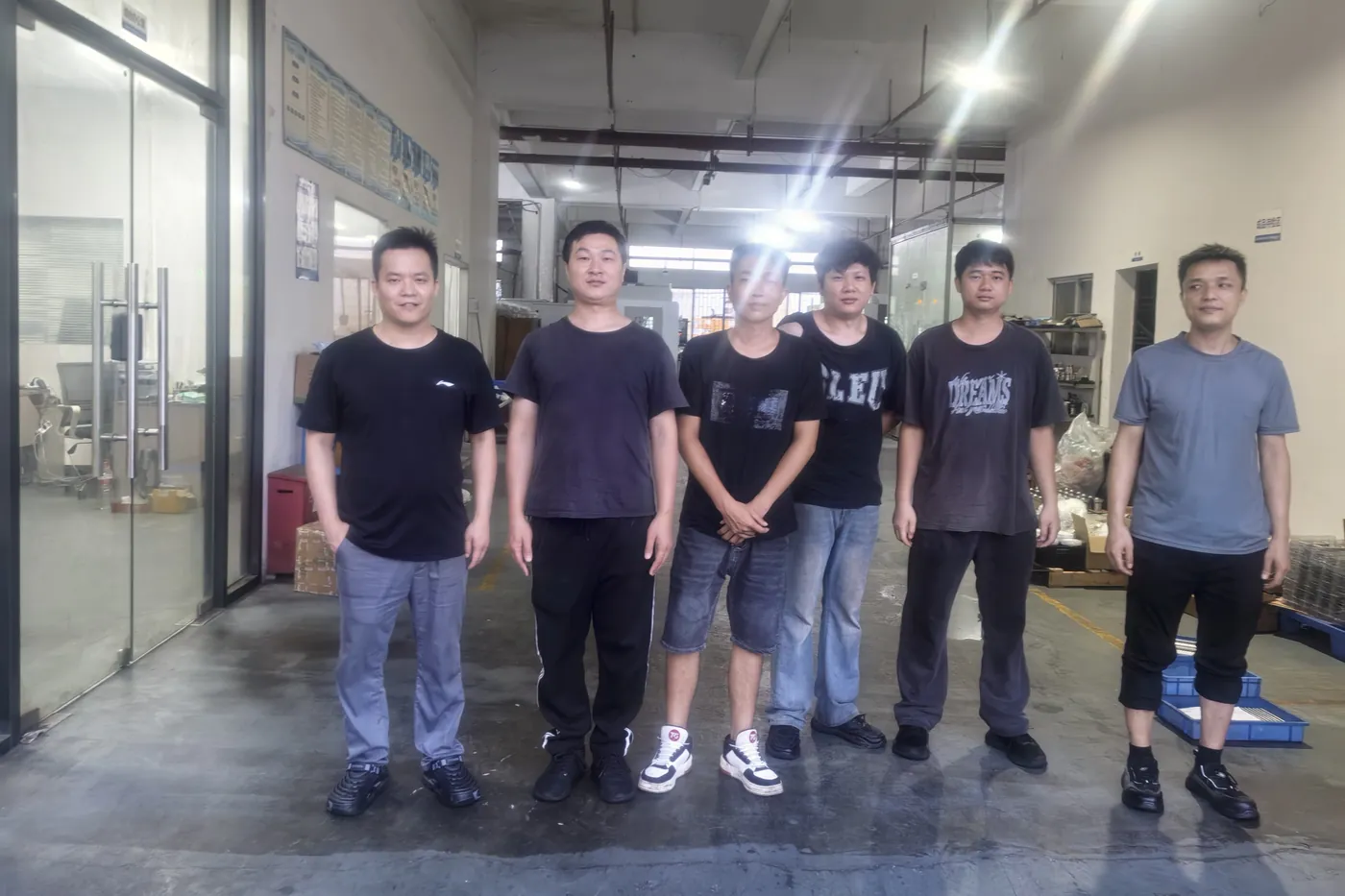 Members of the Meili Machining team on the shop floor in Dongguan with CNC machines behind them