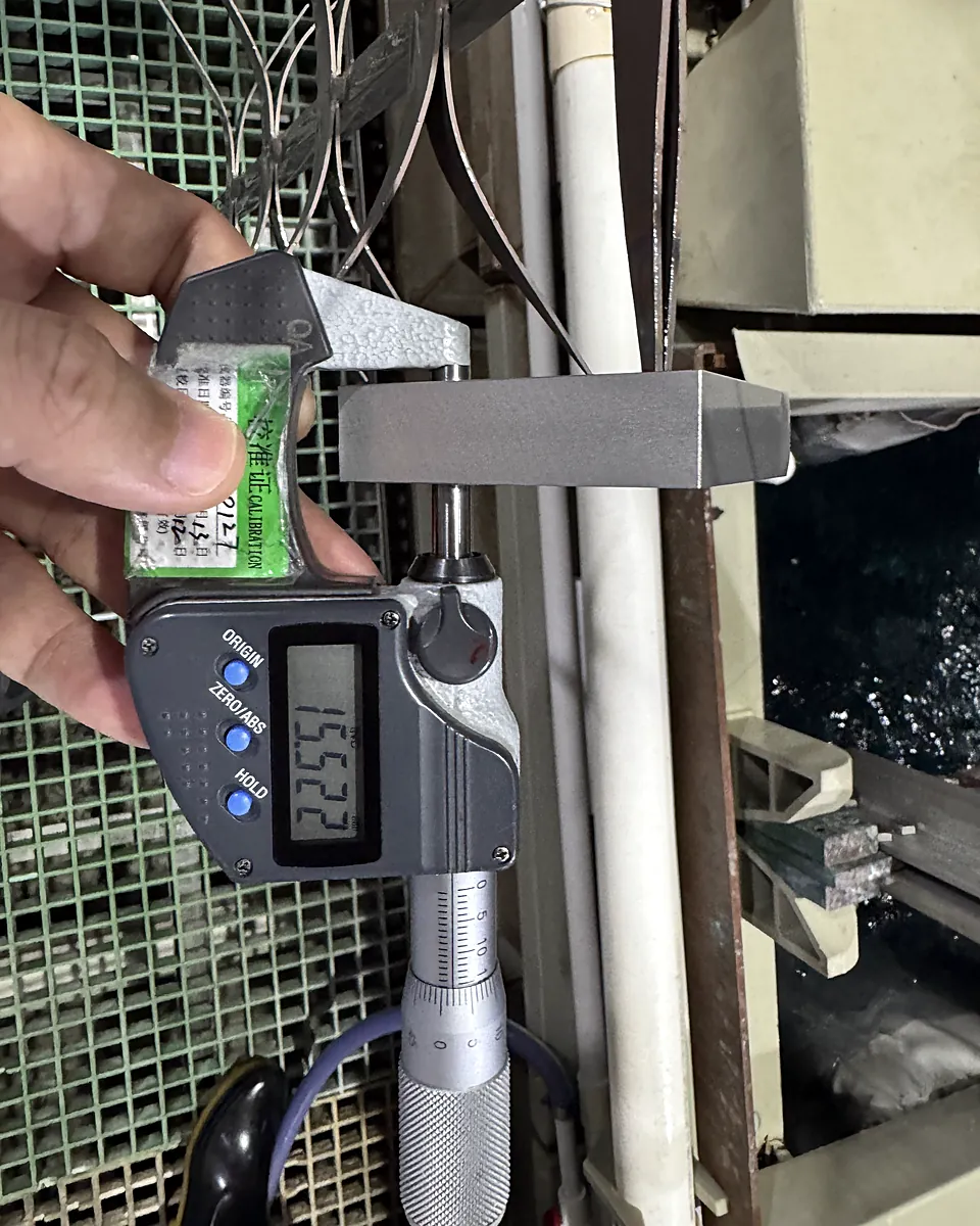 Digital micrometer measuring an anodized aluminum block at the anodizing line