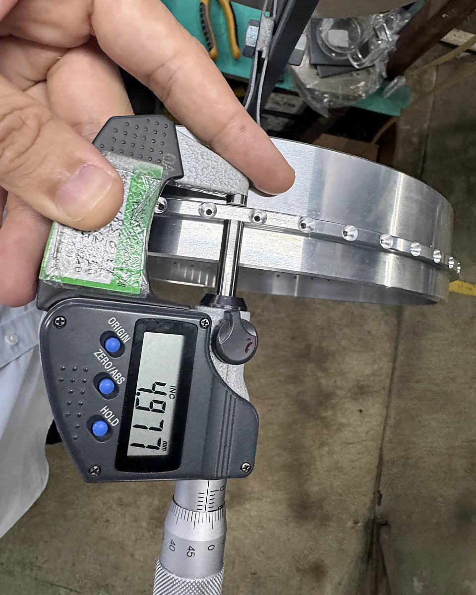 Digital micrometer measuring the rim of a large aluminum disc before hard anodizing