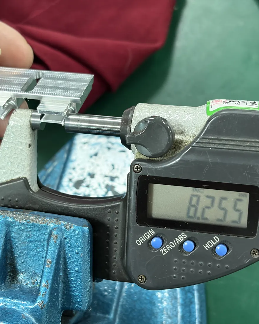 Digital micrometer reading 8.255 mm on a machined aluminum part