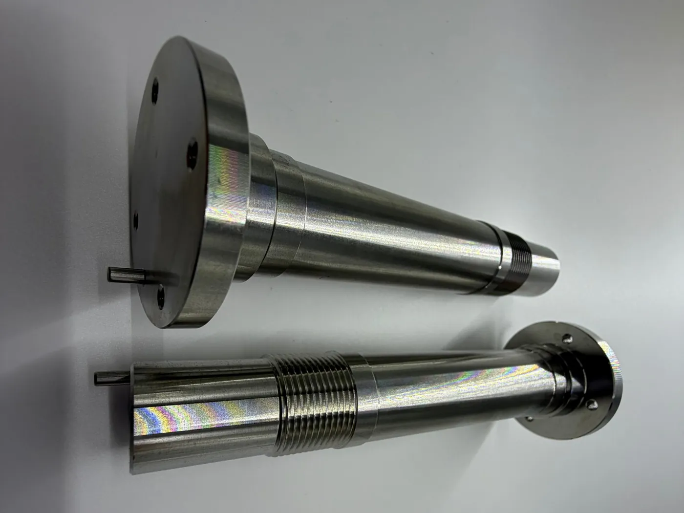 Two turned stainless shafts with flanges and threads, with the Ø3 mm r8 pins from the press fit case pressed in