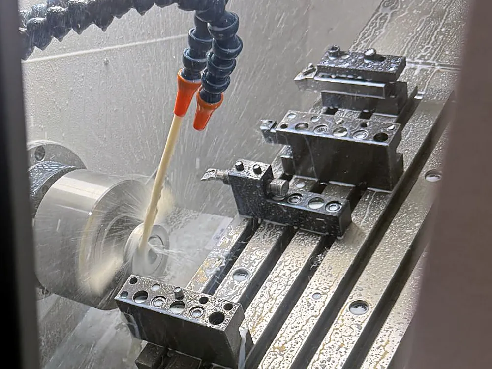 Stainless steel part being turned on a CNC lathe in the Meili factory, with coolant aimed at the cutting edge