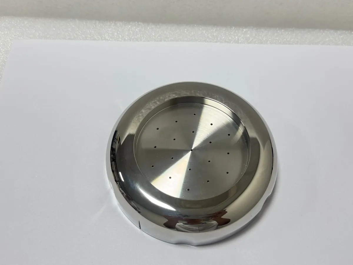 Turned stainless steel cover with a mirror-like outer surface and a turned inner face with small holes